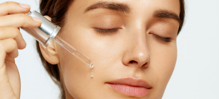 Mujer aplicándose producto en el rostro con un gotero