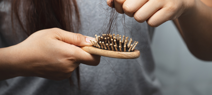 mujer limpiando un cepillo lleno de pelos