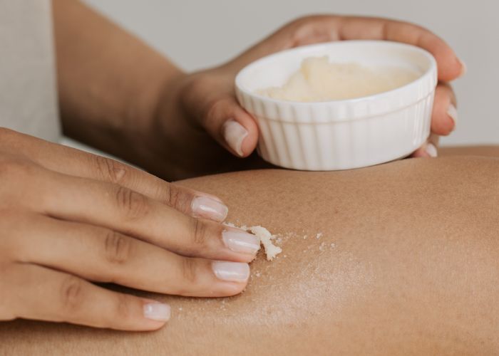 mujer aplic&aacute;ndose crema natural sobre las piernas
